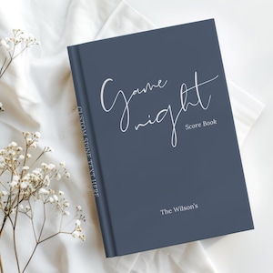 May include: A dark blue hardcover score book with white text that reads Game night Score Book and The Wilson's on the front cover, and CUSTOM SPINE TEXT HERE printed vertically along the spine of the book in a clean, sans-serif font.