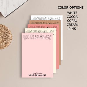 K&ouml;nnte beinhalten: Stapel von rosa, cremefarbenem, korallenfarbenem, kakaofarbenem und wei&szlig;em Notizblockpapier mit einem Rand aus medizinischen Symbolen. Das unterste Blatt tr&auml;gt den Text "a note from Nicole Brown, NP".