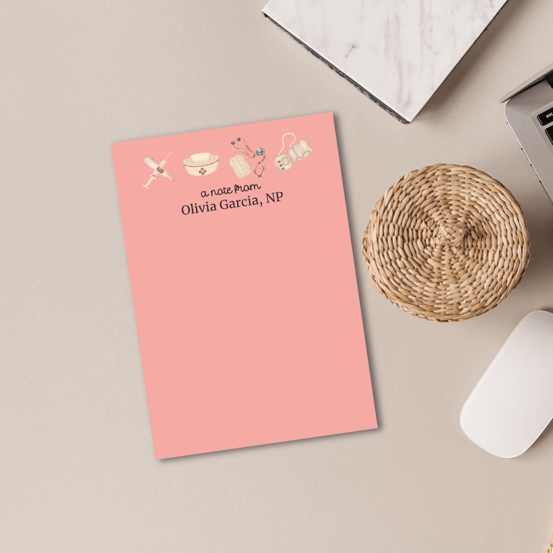 May include: A pink notepad with a note from Olivia Garcia, NP. The notepad has a design of medical tools including a stethoscope, a syringe, a bandage, a pill bottle, and a nurse's cap.