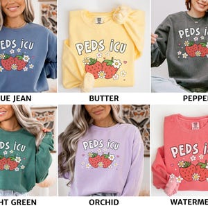 May include: Six different colored sweatshirts with the text "PEDS ICU" and a cartoon image of two strawberries with green leaves and white flowers. The sweatshirts are in the colors blue jean, butter, pepper, light green, orchid, and watermelon.