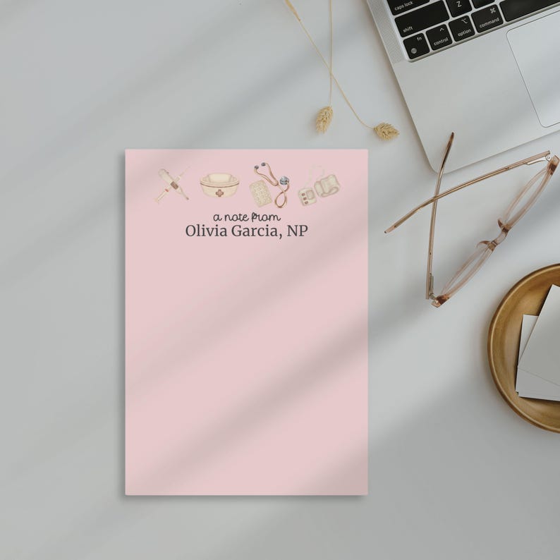 May include: A pink notepad with a note from Olivia Garcia, NP. The notepad has a watercolor illustration of medical supplies, including a stethoscope, a pill bottle, a syringe, and a medical bag.
