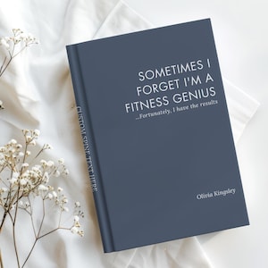 May include: A dark blue hardcover book with white text on the front cover that reads: SOMETIMES I FORGET I'M A FITNESS GENIUS ...Fortunately, I have the results. The author name Olivia Kingsley is printed below, and the spine says CUSTOM SPINE TEXT HERE.