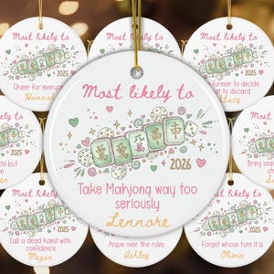 May include: A collection of round white ceramic ornaments featuring illustrations of mahjong tiles and dice. Each ornament displays the text Most likely to, a unique phrase, the year 2025 or 2026, and a personalized name in pink and orange script.