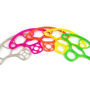 May include: A selection of brightly coloured hand exercisers arranged in an arc. The exercisers are in shades of grey, pink, orange, yellow, and green. Each has a unique design with various openings and shapes, suggesting a focus on hand strength and dexterity.