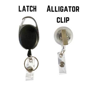 May include: Two badge reels against a white backdrop. The left reel is black with a silver latch. The right reel is clear with a silver alligator clip. The text "LATCH" and "ALLIGATOR CLIP" are above the reels.
