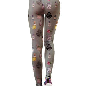 May include: Gray leggings with a repeating pattern of essential oil bottles, diffusers, and floral accents. The leggings feature the text "there's oil for that" in a drop shape. The model is wearing blue and purple sneakers.