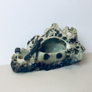 Peut inclure: Une sculpture en pierre verte sculptée d'un oiseau perché sur une branche avec des fleurs. La sculpture a un petit bol rond en pierre verte avec des taches noires.