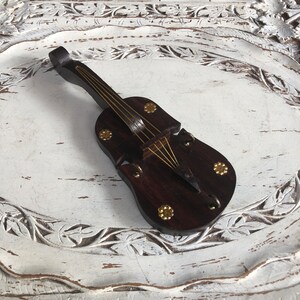 May include: A dark brown wooden violin with gold accents. The violin is a decorative piece and has a carved design.