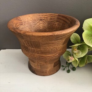 Peut inclure: Un bol en bois avec un design segmenté unique. Le bol est en bois brun clair et a une base large et arrondie.
