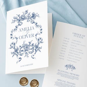 May include: A wedding invitation suite with a blue floral design on white card. The invitation displays the names "Amelia & Oliver" and the date "31 October 2026". Two gold wax seals are visible at the bottom of the image.
