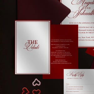 May include: A wedding invitation suite with a burgundy and white color scheme. The suite includes an invitation, RSVP card, and details card. Decorative heart-shaped embellishments are scattered around the cards.