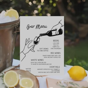 May include: A bar menu featuring a black and white illustration of a hand pouring wine. The menu lists beers, red and white wines, cocktails, and soft drinks. Sliced lemons and a whole lemon are on a wooden surface.