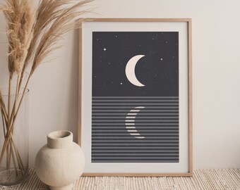 May include: A framed print with a minimalist design featuring a white crescent moon against a dark blue background with white stars. The bottom half of the print features a repeating pattern of horizontal grey and white stripes with a white crescent moon in the centre.