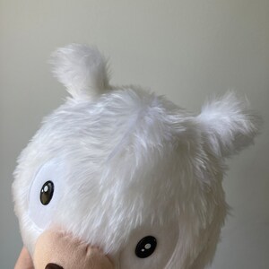 Puede incluir: Juguete de peluche blanco con grandes ojos negros y una nariz marr&oacute;n. El juguete tiene forma de oso y tiene una pelusa blanca y esponjosa.