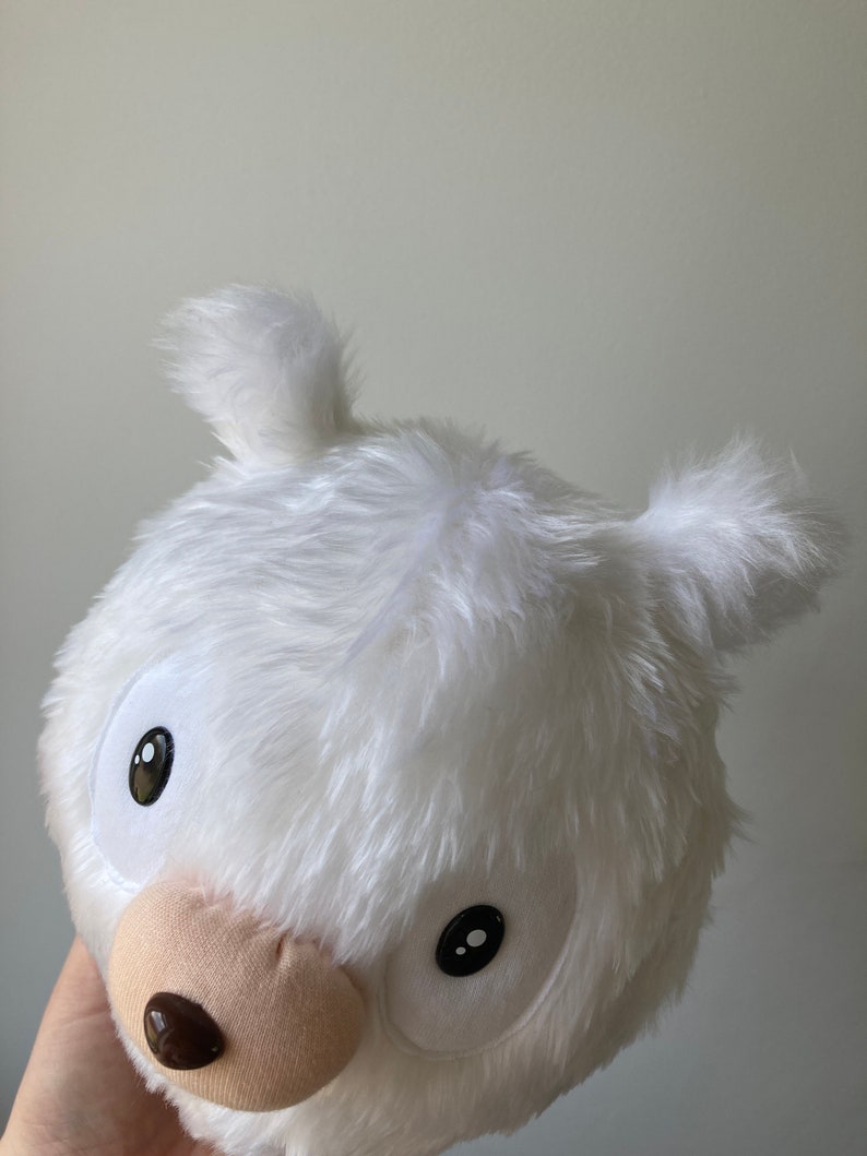 Puede incluir: Juguete de peluche blanco con grandes ojos negros y una nariz marr&oacute;n. El juguete tiene forma de oso y tiene una pelusa blanca y esponjosa.