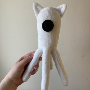 May include: White plush toy with a black button for an eye and four long legs.