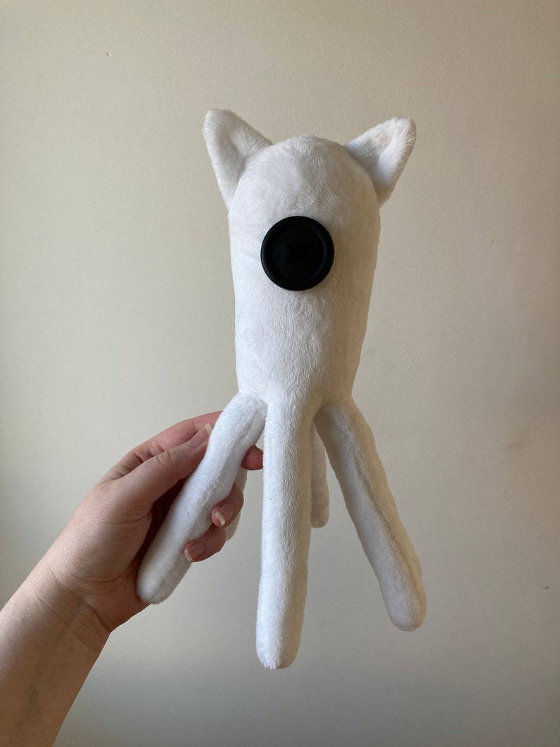 May include: White plush toy with a black button for an eye and four long legs.