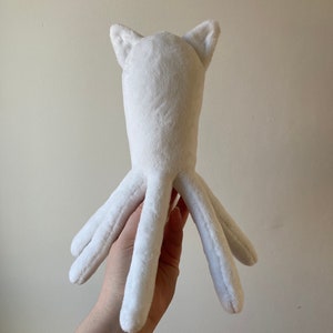 May include: White plush toy shaped like an octopus with cat ears. The toy has six tentacles and is made of soft, fluffy material.