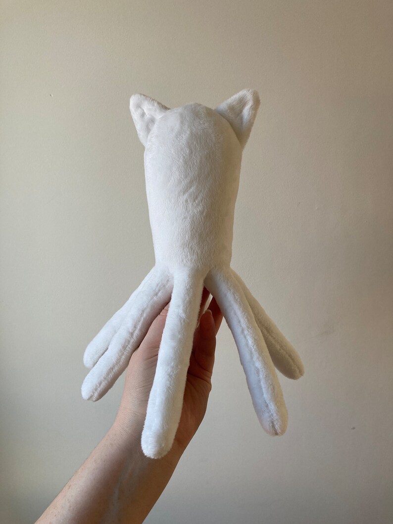 May include: White plush toy shaped like an octopus with cat ears. The toy has six tentacles and is made of soft, fluffy material.