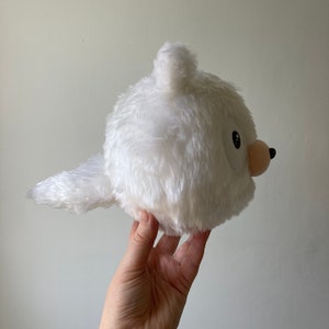 Puede incluir: Juguete de peluche blanco con forma de animal redondo con una cola larga. El juguete tiene una peque&ntilde;a nariz rosa y un ojo negro.