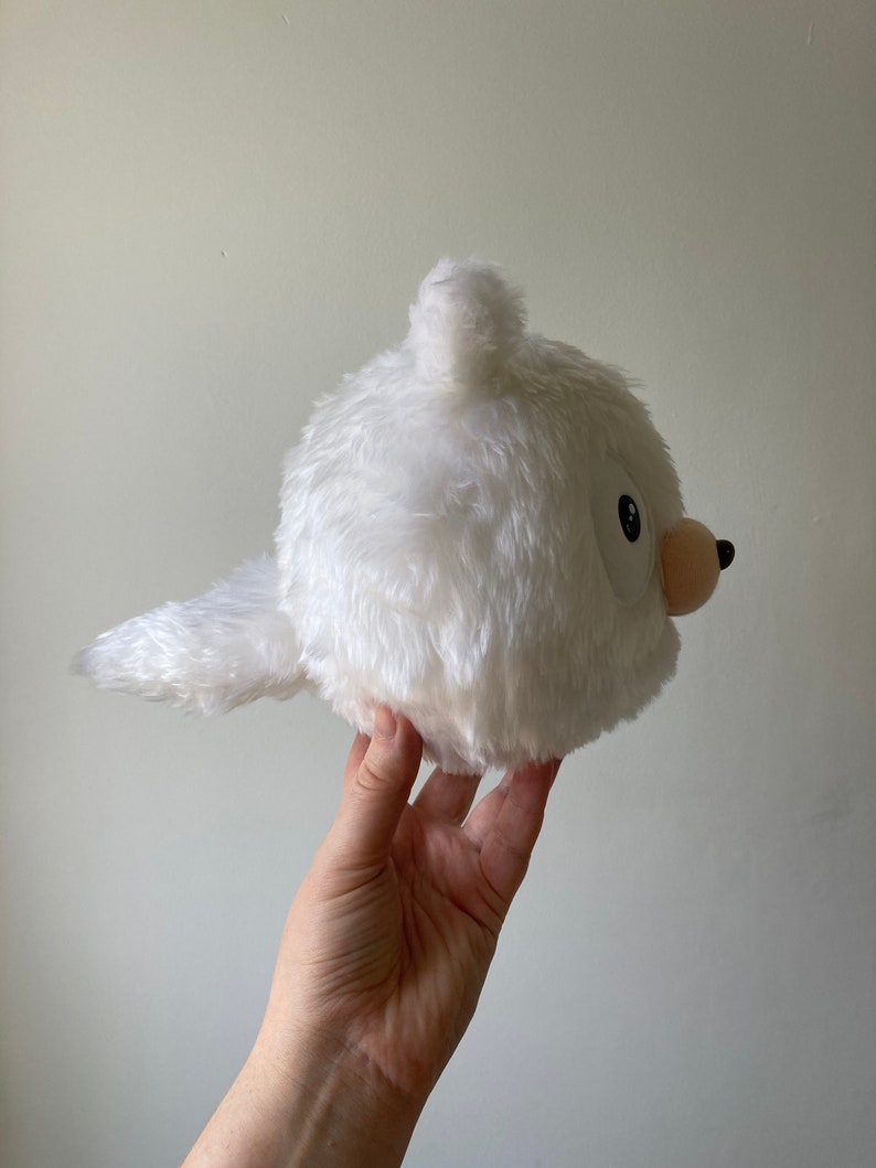 Puede incluir: Juguete de peluche blanco con forma de animal redondo con una cola larga. El juguete tiene una peque&ntilde;a nariz rosa y un ojo negro.