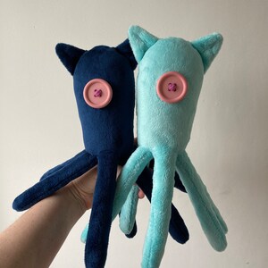 May include: Two plush octopus toys, one blue and one light blue, with pink button eyes.