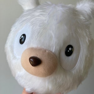 Puede incluir: Juguete de peluche blanco con cabeza redonda, ojos negros y nariz marr&oacute;n. El juguete est&aacute; hecho de un material suave y esponjoso.