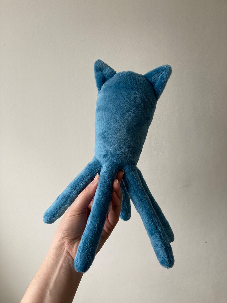 May include: A blue plush octopus with long, thin tentacles and two small ears on top of its head.