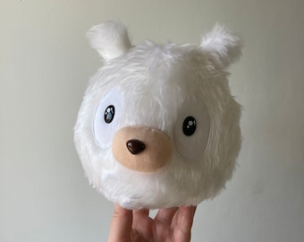 May include: White plush toy shaped like a bear's head with black eyes, a brown nose, and a white fluffy body.