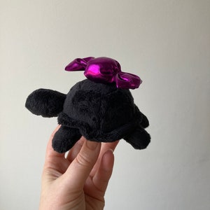 Schwarze Schildkröte mit Candy Art Plüschtier - Über der Gartenmauer.