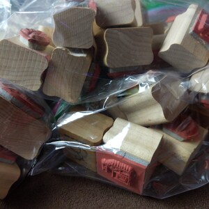 May include: A plastic bag filled with wooden stamps. The stamps have various shapes and sizes, and some have red ink pads attached.