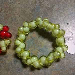 May include: A yellow beaded bracelet with a white tag attached. The beads are round and have a translucent appearance.