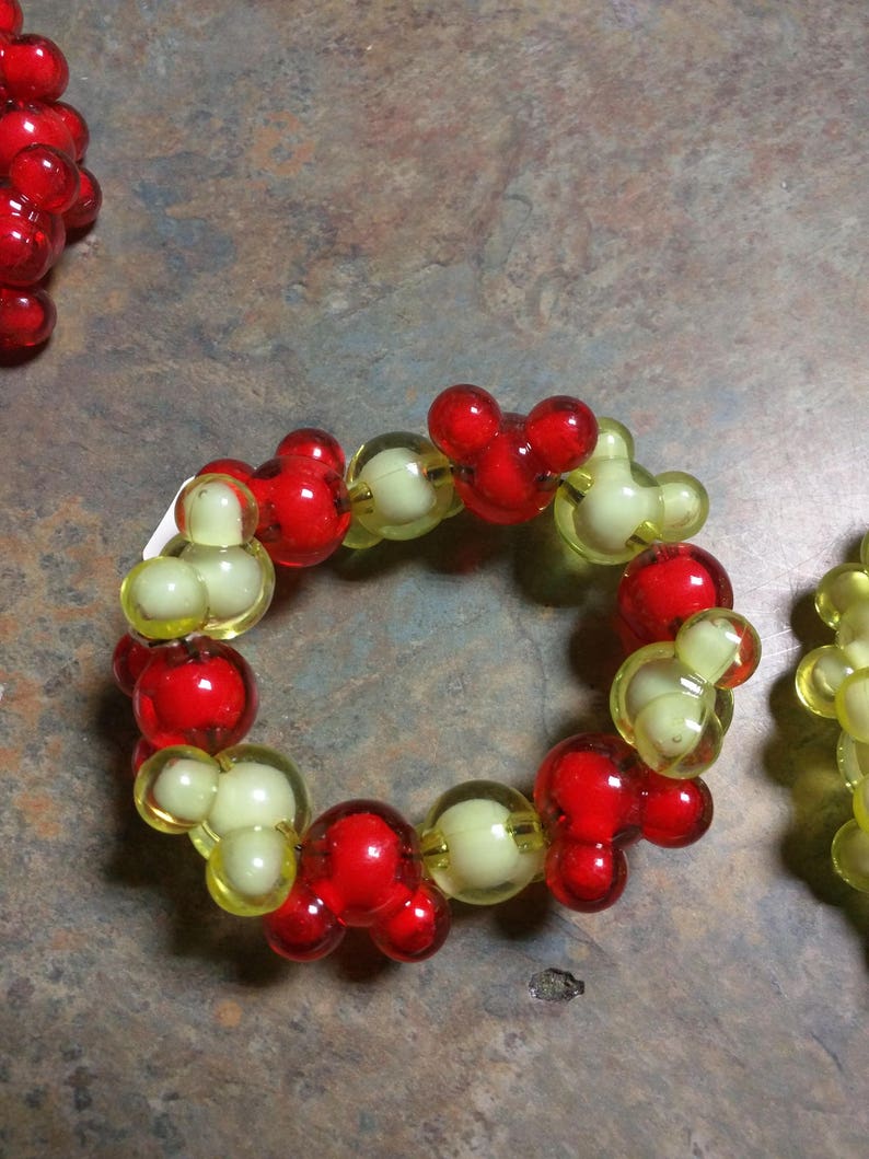 May include: A red and yellow beaded bracelet with Mickey Mouse head shaped beads.