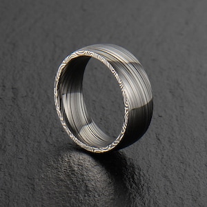 Puede incluir: Un anillo de plata con un diseño único. El anillo está hecho de metal y tiene un acabado pulido.
