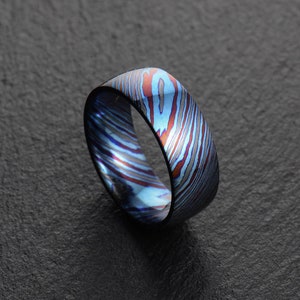 May include: A blue and red patterned metal ring. The ring is made of a unique material with a swirling pattern.