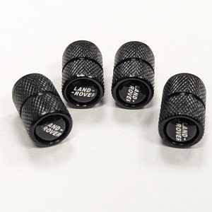 May include: Set of four black metal tyre valve stem caps with the Land Rover logo in white lettering.