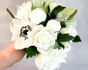 May include: A bouquet of white paper flowers, including roses, anemones, and peonies, with green paper leaves.