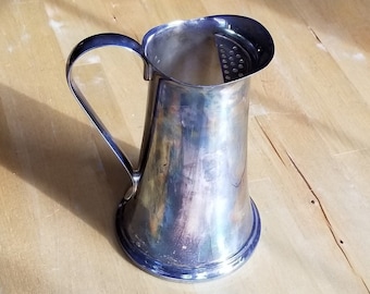May include: A silver pitcher with a strainer on the top. The pitcher has a rounded body and a handle.