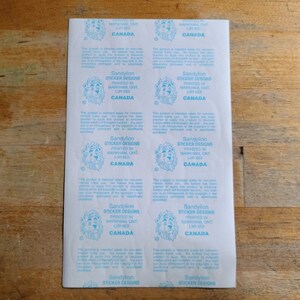 May include: A sheet of stickers with a lion logo and the text "Sandylion Sticker Designs Printed in Markham, ONT L3R 8E3 Canada".