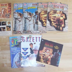 May include: A collection of Indiana Jones themed books and magazines. The books include "Indiana Jones and the Last Crusade" and "Indiana Jones Chronicles: The Mummy's Curse". The magazines include "The Official Indiana Jones Gazette" and "Making Movies".