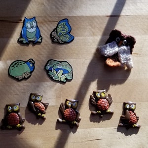 May include: A collection of colorful felt and fabric appliques featuring owls, butterflies, and insects. The appliques are perfect for adding a whimsical touch to crafts, clothing, or home decor.