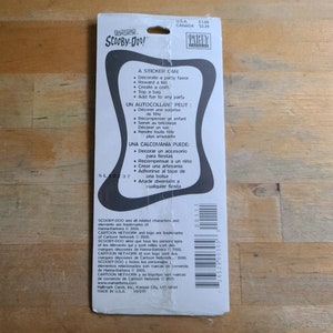 May include: A sticker sheet featuring Scooby-Doo and the gang. The sticker sheet is blue and white with a black border. The text on the sticker sheet reads "A sticker can: Decorate a party favor, Reward a kid, Create a craft, Top a bag, Add fun to any party".