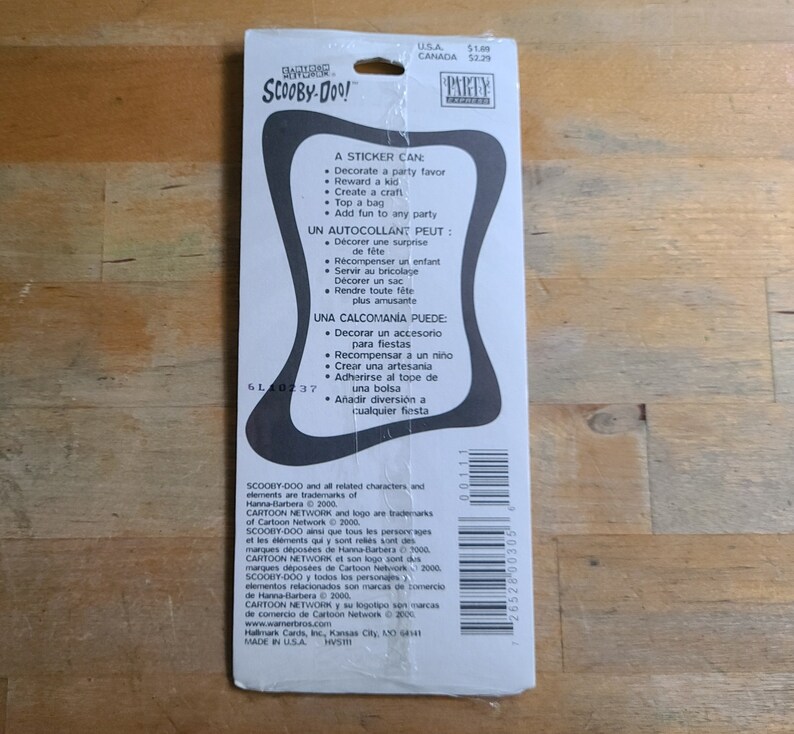 May include: A sticker sheet featuring Scooby-Doo and the gang. The sticker sheet is blue and white with a black border. The text on the sticker sheet reads "A sticker can: Decorate a party favor, Reward a kid, Create a craft, Top a bag, Add fun to any party".