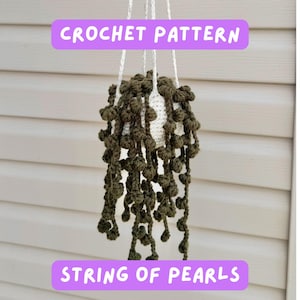 May include: A crocheted hanging planter with a white pot and olive green "String of Pearls" plant. The text "CROCHET PATTERN" and "STRING OF PEARLS" are displayed on the image.