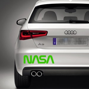 Pode incluir: Parte traseira de um carro branco com o logotipo verde da NASA. O carro tem uma placa de licença e tubos de escape duplos. Luzes traseiras vermelhas.