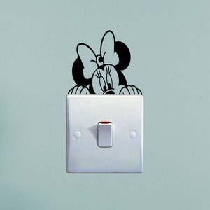 May include: A white light switch with a black and white cartoon mouse peeking out from behind it.