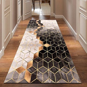 May include: Geometric patterned runner rug in a hallway. The rug features a repeating pattern of black, gold, and gray geometric shapes. The rug is rectangular and placed on a wooden floor, adding a modern touch to the space.