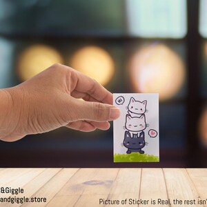 Sticker rectangulaire La tour des chats avec amour et disant « bonjour » derrière une haie, 3 x 2 po.