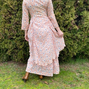 May include: A white maxi dress with a floral print in shades of orange and blue. The dress has a ruffled hem and long sleeves.