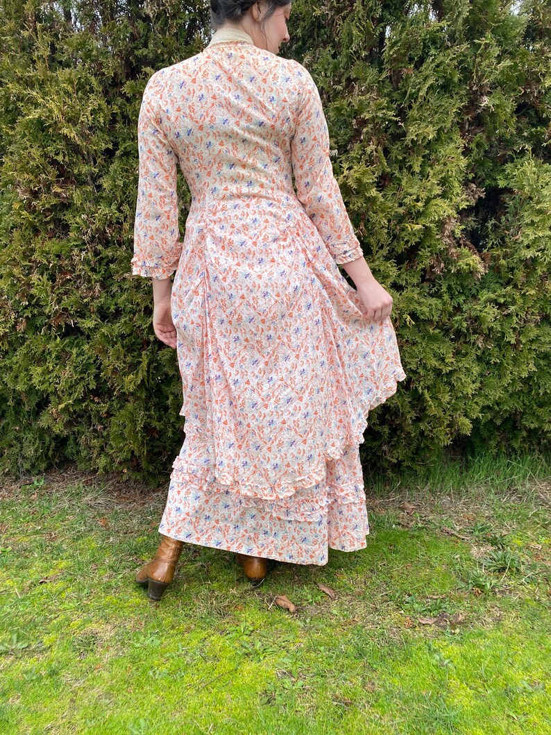 May include: A white maxi dress with a floral print in shades of orange and blue. The dress has a ruffled hem and long sleeves.